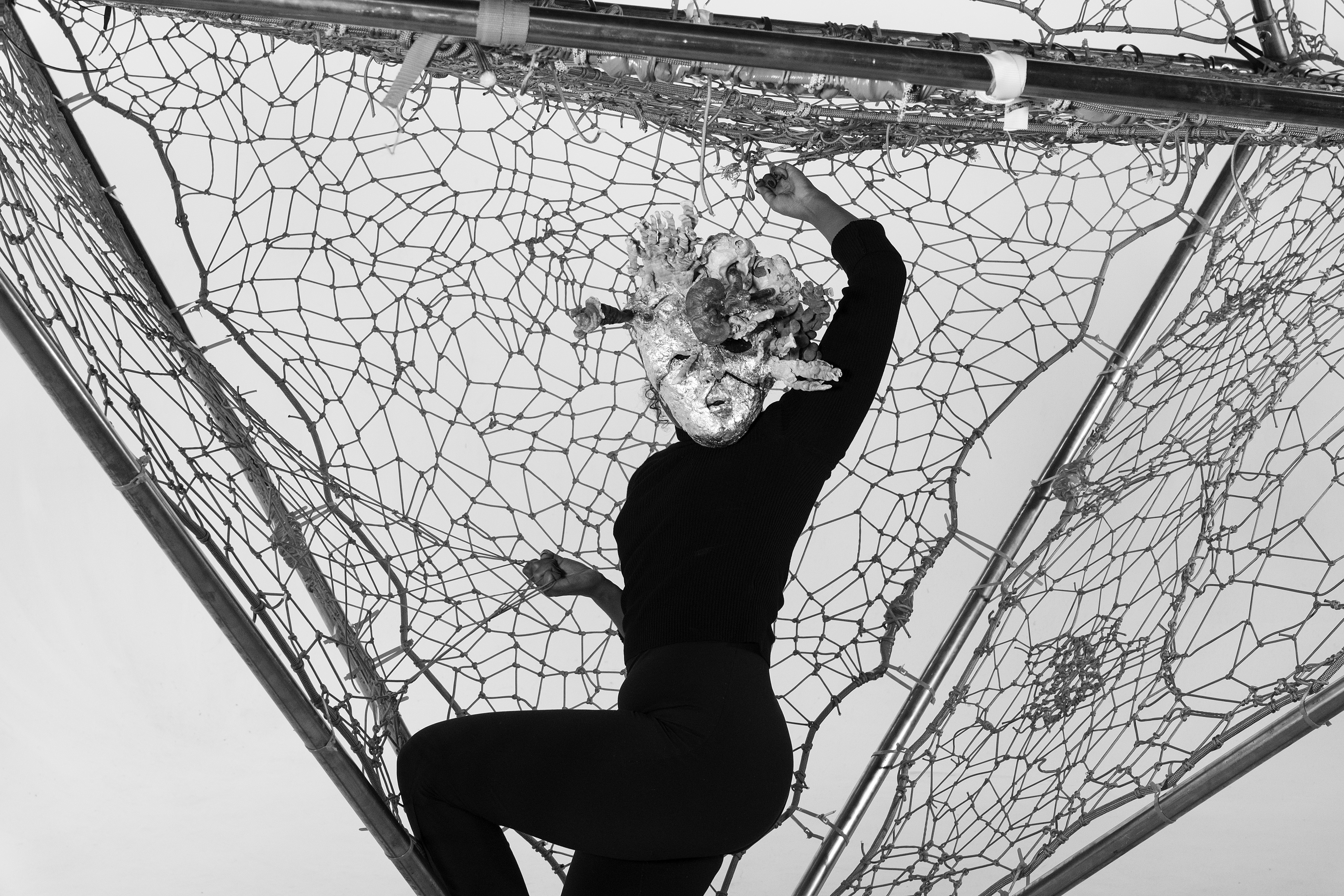 The Teratoma: masked performer in a rope net